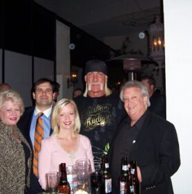 Hulk Hogan et al. standing next to a wine glass posing for the camera